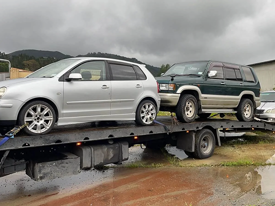 Tow truck transporting three scrap cars for removal in Levin